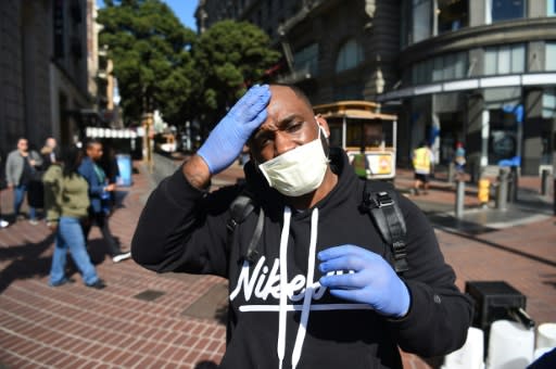 A man adjusts his mask and gloves, a precaution to protect himself from coronavirus, while walking by cable car in San Francisco, California