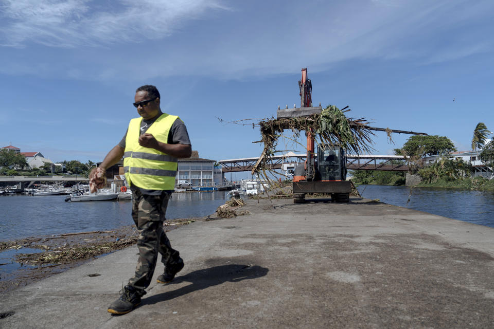 Workers clean up trees and debris on the marina of Saint-Gilles les Bains on the French Indian Ocean island of Reunion, Tuesday, Jan. 16, 2024. Tropical cyclone Belal had battered the French island of Reunion, where the intense rains and powerful winds left about a quarter of households without electricity after hitting Monday morning, according to the prefecture of Reunion. (AP Photo/Lewis Joly)