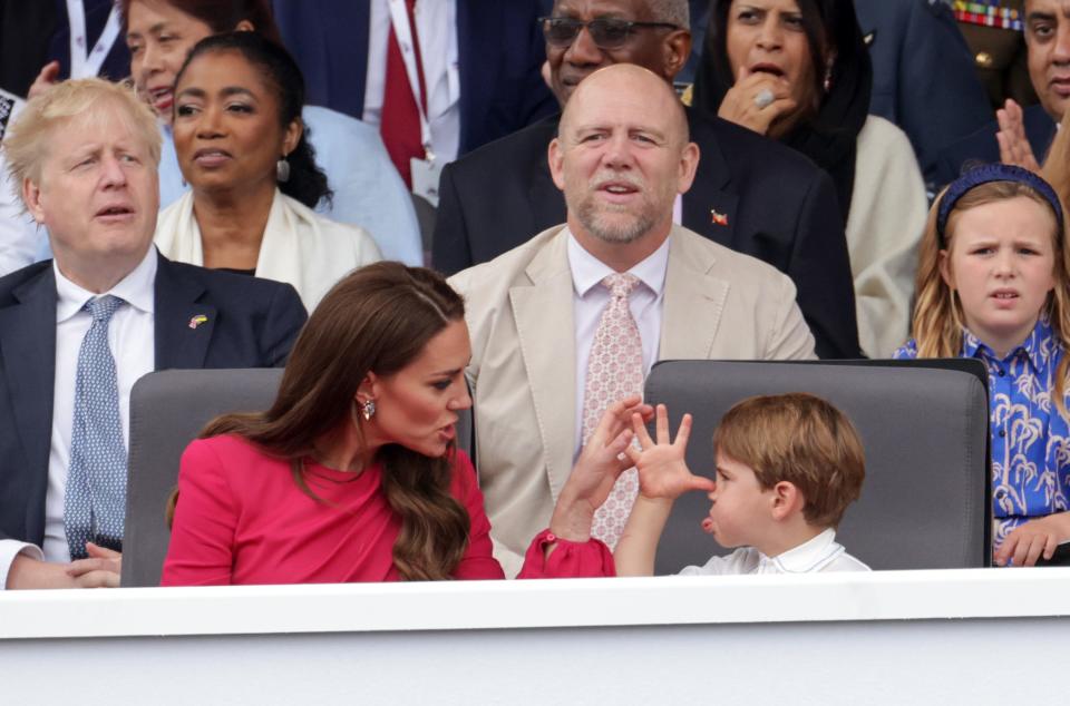 Prince Louis makes a funny expression with his tongue and hands to Kate Middleton