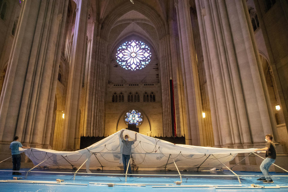 Volunteers raise a tent while building a field hospital at the Cathedral of St. John the Divine, Wednesday, April 8, 2020, in New York. Volunteers assembled and placed 56 beds in five chapels and raised one of several tents in the nave. Work will continue Thursday. (AP Photo/Mary Altaffer)