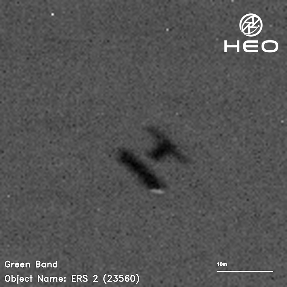 a blurry black-and-white image of an H-shaped satellite against a background of a few dozen stars