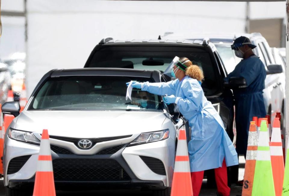 Healthcare workers prepare to test drivers at a drive-through coronavirus testing site outside of Hard Rock Stadium, Friday, June 26, 2020, in Miami Gardens, Fla.