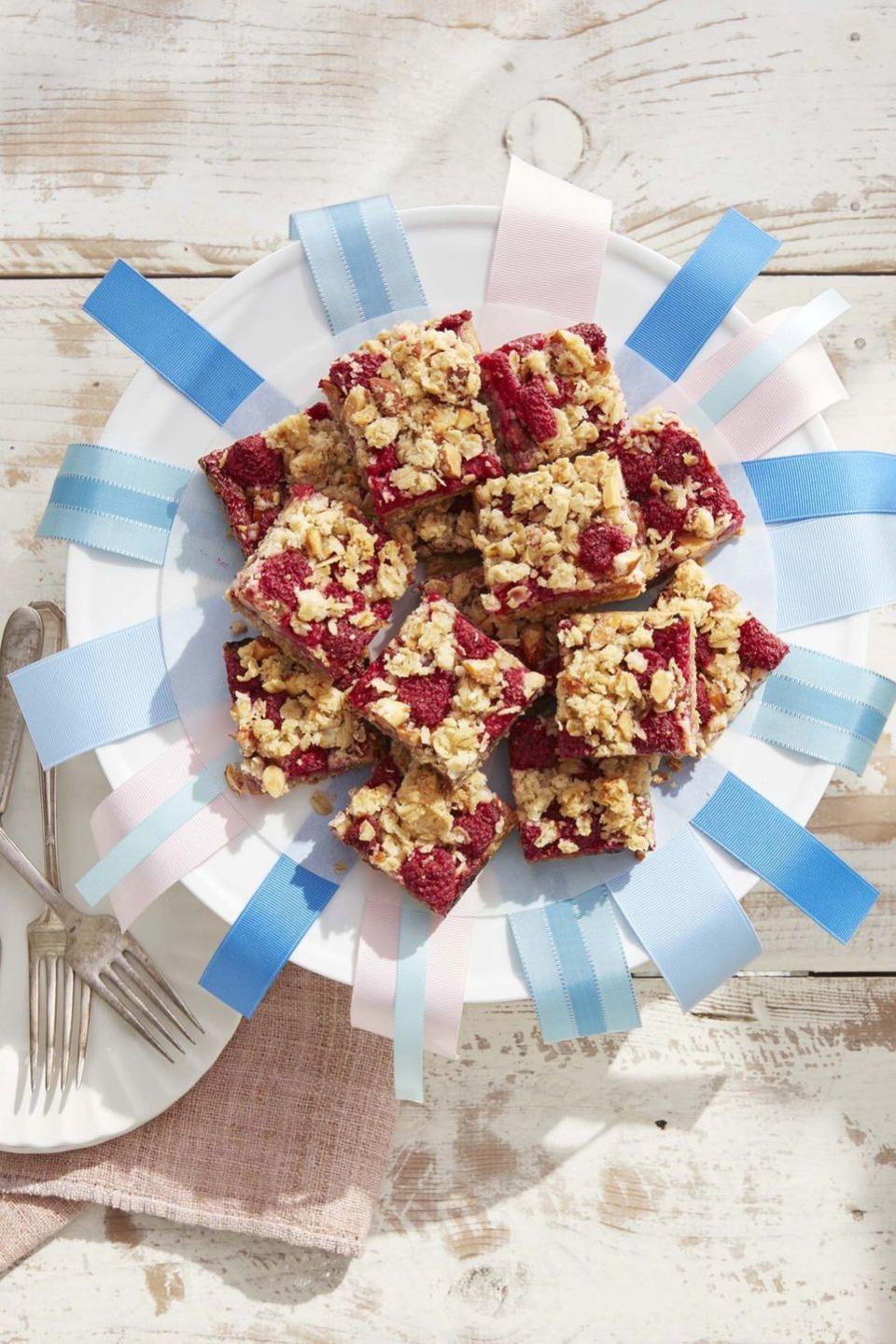 raspberry crumb bars stacked on a plate decorated with ribbons