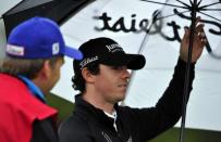 Rory McIlroy of Northern Ireland shelters from the rain during his first round on the opening day of the 2012 Open Championship at Royal Lytham and St Annes in Lytham