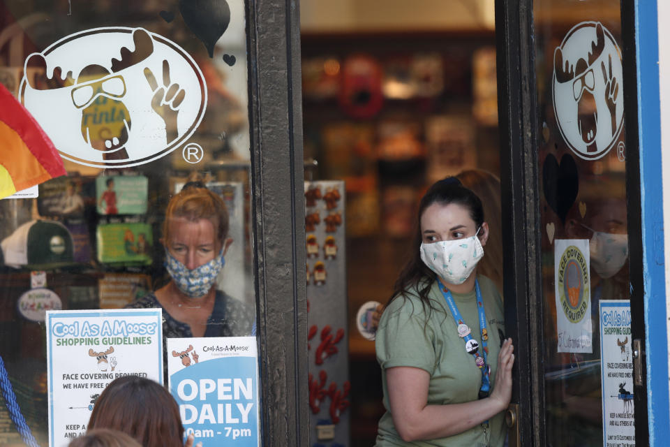 A worker at a gift shop regulated the number of customers allowed in the store due to the coronavirus pandemic, Thursday, July 30, 2020, in Portland, Maine. State officials reported more cases of COVID-19. (AP Photo/Robert F. Bukaty)