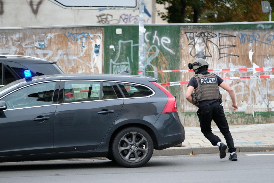 Police officer runs on a road in Halle, Germany, Wednesday, Oct. 9, 2019. One or more gunmen fired several shots on Wednesday in the German city of Halle. Police say a person has been arrested after a shooting that left two people dead. (Sebastian Willnow/dpa via AP)