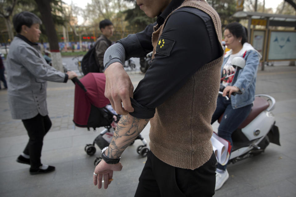 In this March 28, 2019, photo, Yin Hao, who also goes by Yin Qiang, rolls up his sleeve while walking along a street in Xi'an, northwestern China's Shaanxi Province. Officially, pain pill abuse is an American problem, not a Chinese one. But people in China have fallen into opioid abuse the same way many Americans did, through a doctor's prescription. And despite China's strict regulations, online trafficking networks, which facilitated the spread of opioids in the U.S., also exist in China. (AP Photo/Mark Schiefelbein)