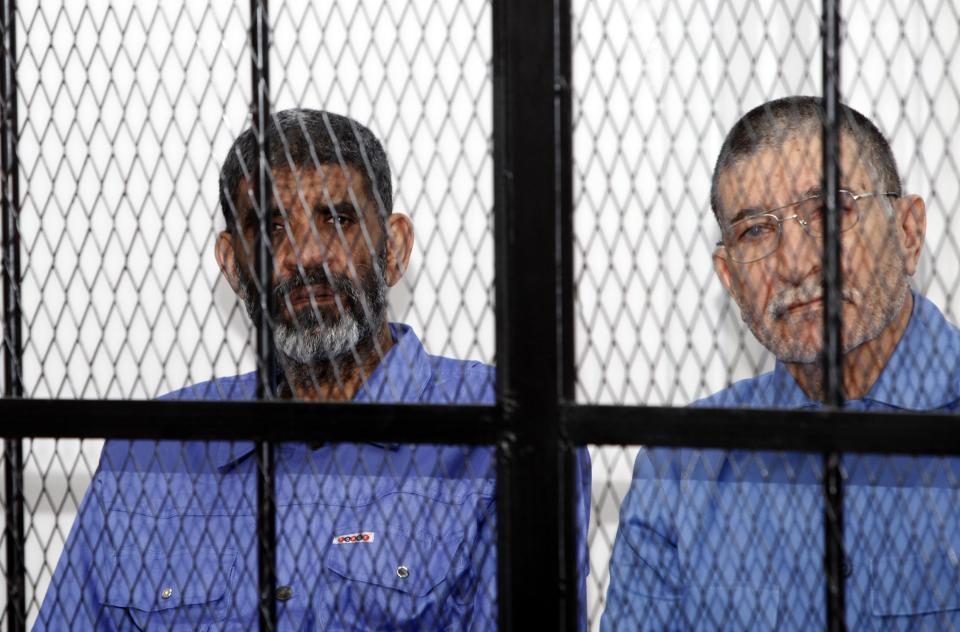 Abdullah al-Senussi (L), ex-spy chief in Muammar Gaddafi's government and Buzeid Dorda, ex-intelligence chief, sit behind bars during a hearing at a courtroom in Tripoli April 14, 2014. Libyan prosecutors opened the trial of deposed leader Muammar Gaddafi's sons and former regime officials on Monday in a major test for the North African state's transition to a democracy. REUTERS/Ismail Zitouny (LIBYA - Tags: POLITICS CIVIL UNREST CRIME LAW TPX IMAGES OF THE DAY)