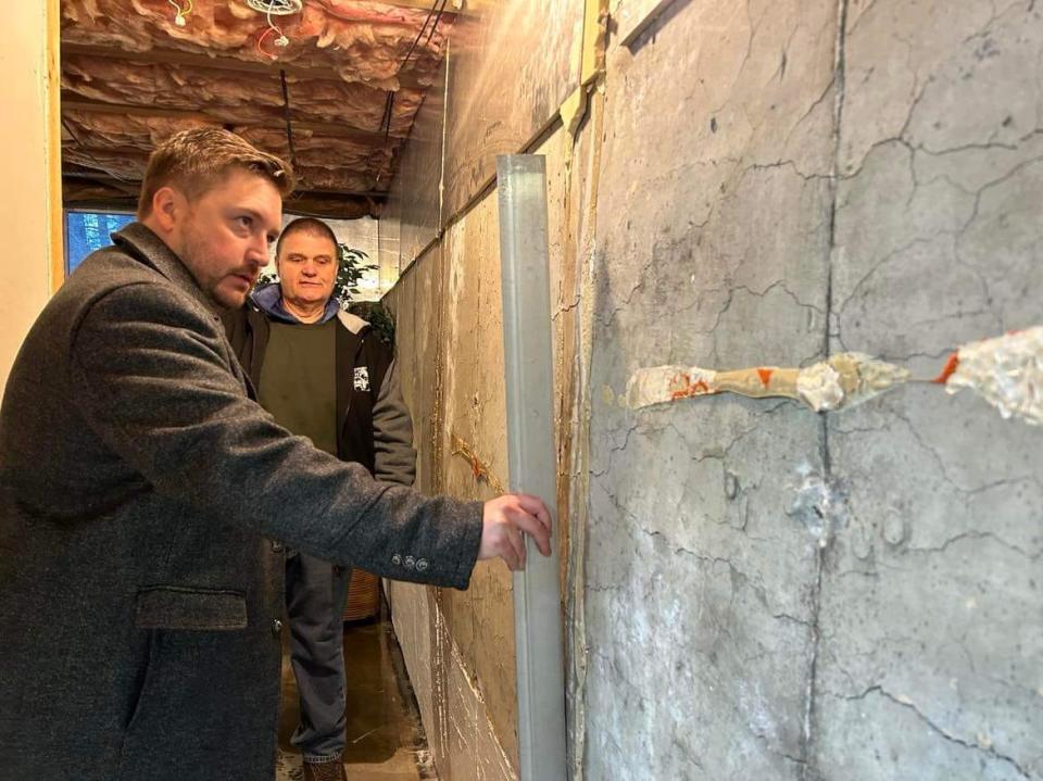 Rep. Jonathan Zlotnik inspects the effects of pyrrhotite-contaminated concrete in the foundation of a home in Winchendon as Rick Riana looks on.