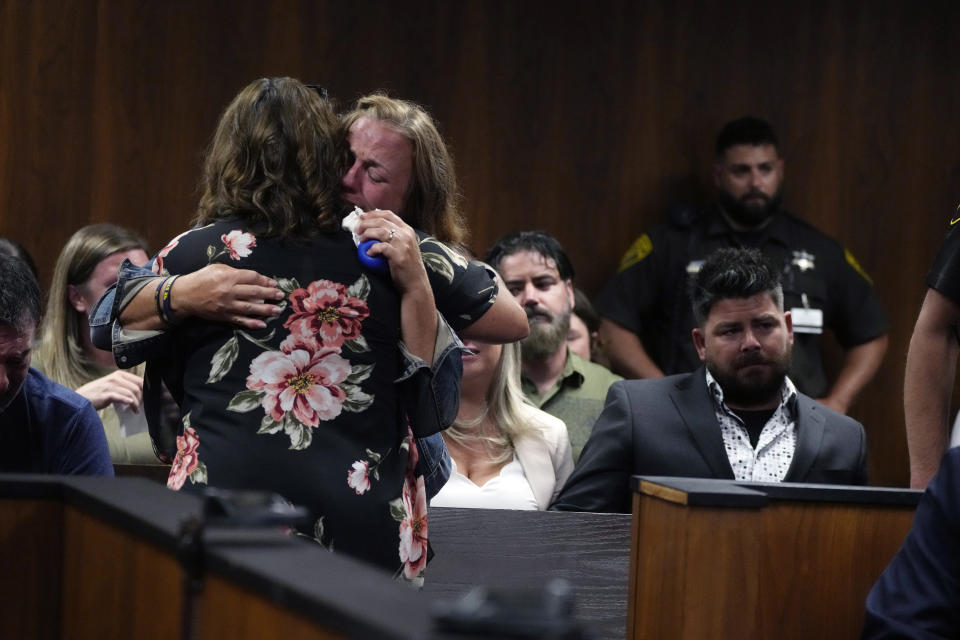 Sheri Myre, background, mother of slain Oxford student Tate Myre, hugs Assistant Principal Kristy Gibson-Marshall in court, Friday, July 28, 2023, in Pontiac, Mich. Prosecutors are making their case that the Michigan teenager should be sentenced to life in prison for killing four students at his high school in 2021. Prosecutors introduced dark journal entries written by Ethan Crumbley, plus chilling video and testimony from a wounded staff member. (AP Photo/Carlos Osorio)