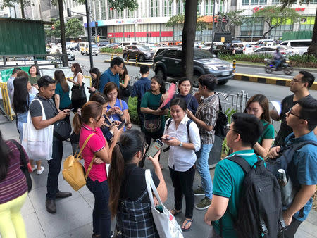 Employees wait outside after being evacuated from the office building after an earthquake in Makati City, Philippines, April 22, 2019. REUTERS/Martin Petty