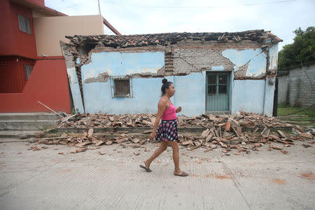 Ximena, 26, an indigenous Zapotec transgender woman also know as Muxe, walks in front of a house destroyed after an earthquake that struck on the southern coast of Mexico late on Thursday, in Juchitan, Mexico, September 10, 2017. REUTERS/Edgard Garrido