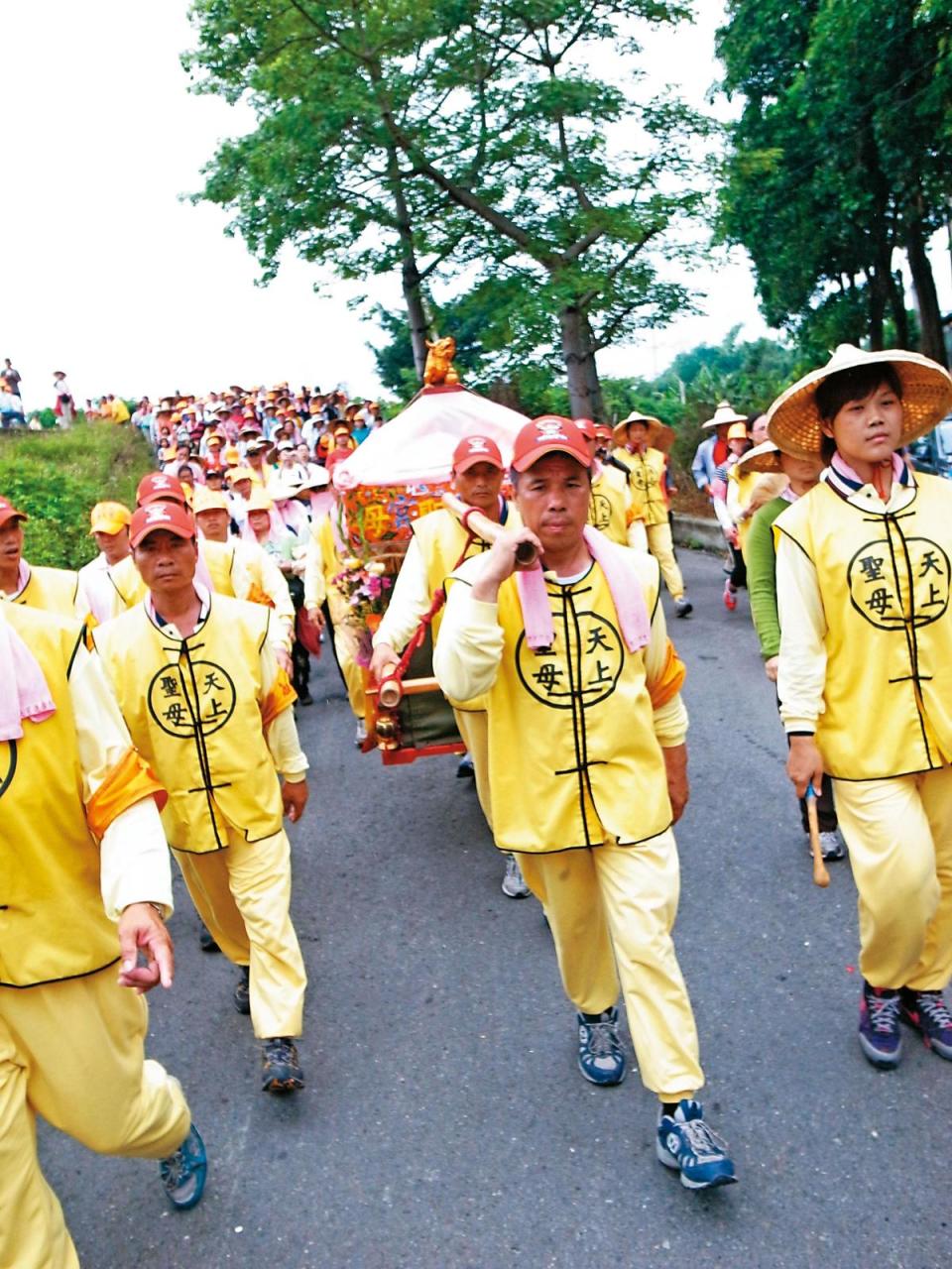 陳弼宏（前方扛轎者）擔任轎班長達30年，他說穿上制服般的黃背心就不能講話，休息時，上廁所或抽菸，都必先脫下背心。（拱天宮文化組提供）