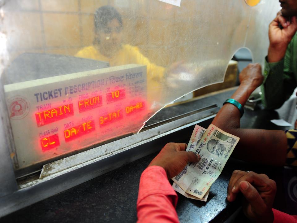 Indian passengers stand in a queue to buy railway tickets.