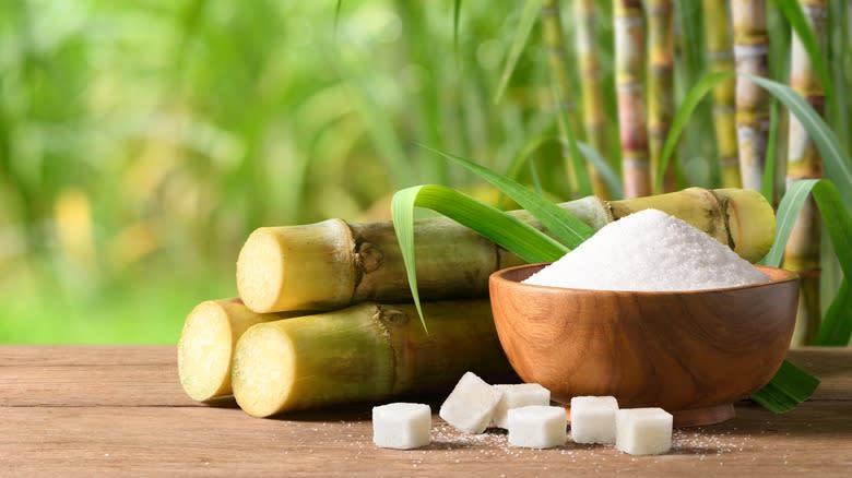 bowl of white sugar with sugarcane