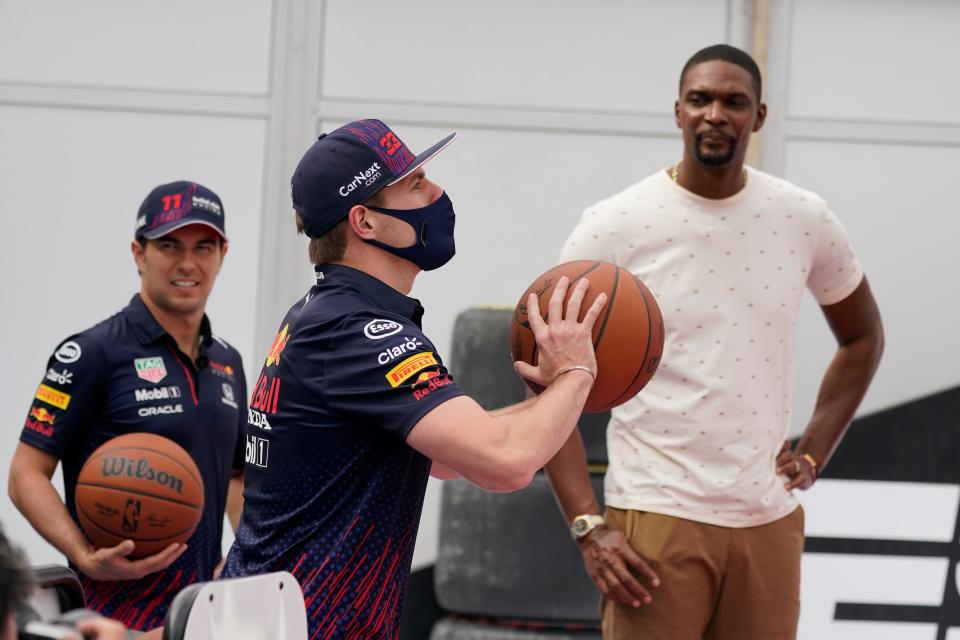 Red Bull driver Max Verstappen, center, shoots baskets as teammate Sergio Perez, left, and former NBA star player Chris Bosh look on. Formula 1 teams took part in a free throw challenge at the Circuit of the Americas to help the NBA celebrate its 75th anniversary.
