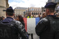 FILE - An anti heath pass demonstrator holds a French flag as he faces police officers outside the Constitutional Council in Paris, Thursday, Aug. 5, 2021. The coronavirus's omicron variant kept a jittery world off-kilter Wednesday Dec. 1, 2021, as reports of infections linked to the mutant strain cropped up in more parts of the globe, and one official said that the wait for more information on its dangers felt like “an eternity.” (AP Photo/Michel Euler, File)
