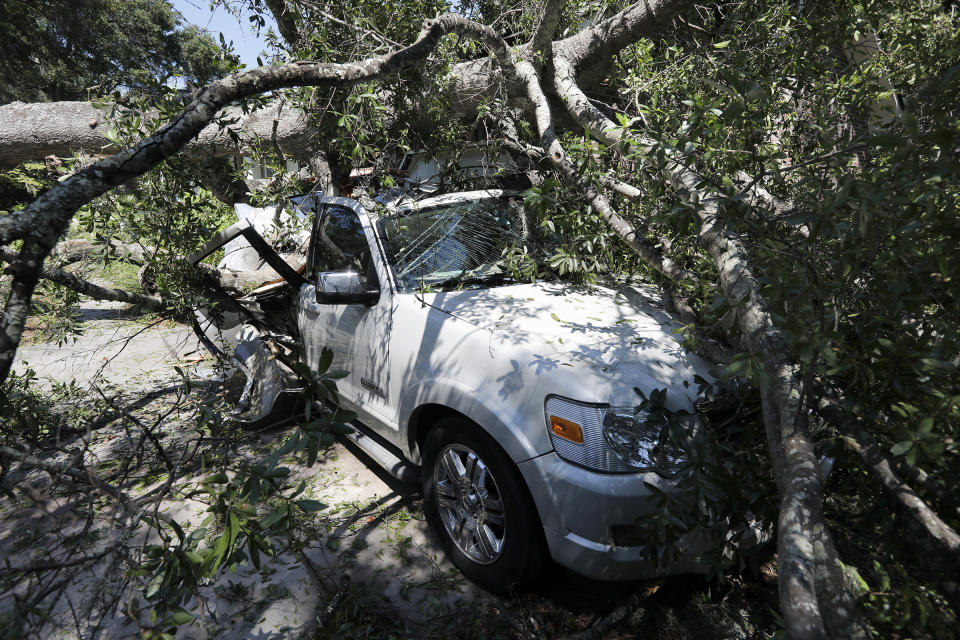 A tree brings smashes a car after Hurricane Dorian passed by James Island, S.C., Friday, Sept. 6, 2019. (AP Photo/Mic Smith)