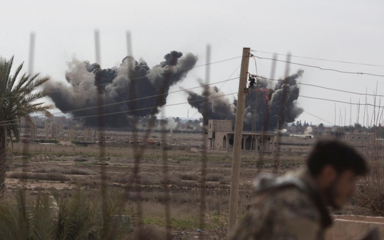 A Syrian Democratic Forces (SDF) fighter ducks as a pair of coalition airstrikes hit territory controlled by Isil near the town of Baghuz  - Sam Tarling