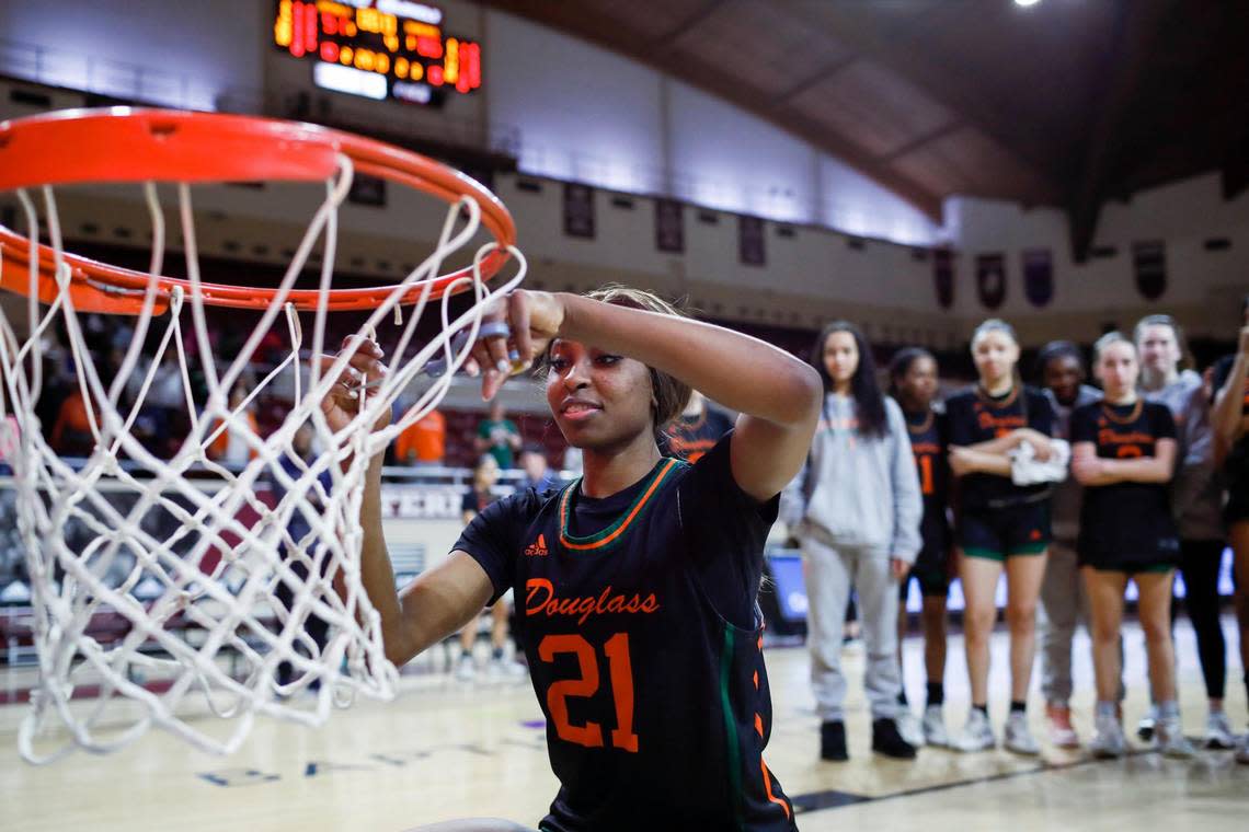 Frederick Douglass’ Ayanna Darrington cuts of part of the net after the Broncos defeated Lexington Catholic in the 11th Region Tournament championship game.