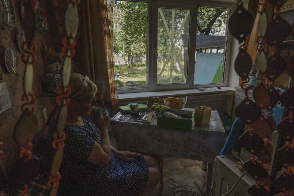 Resident Olena smokes her cigarette after her kitchen's windows broke in the aftermath of a rocket attack at a residential area, in Kramatorsk, eastern Ukraine, Tuesday, July 19, 2022. (AP Photo/Nariman El-Mofty)