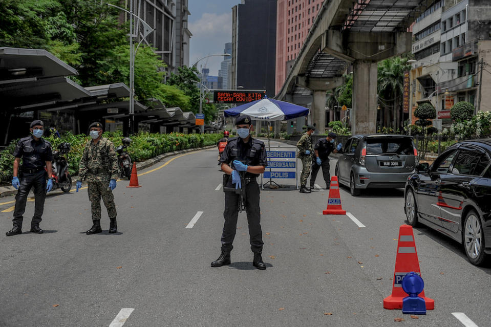 Soldiers and police officers conducting checks at a roadblock during the movement control order (MCO) in Kuala Lumpur March 29, 2020. — Picture by Firdaus Latif