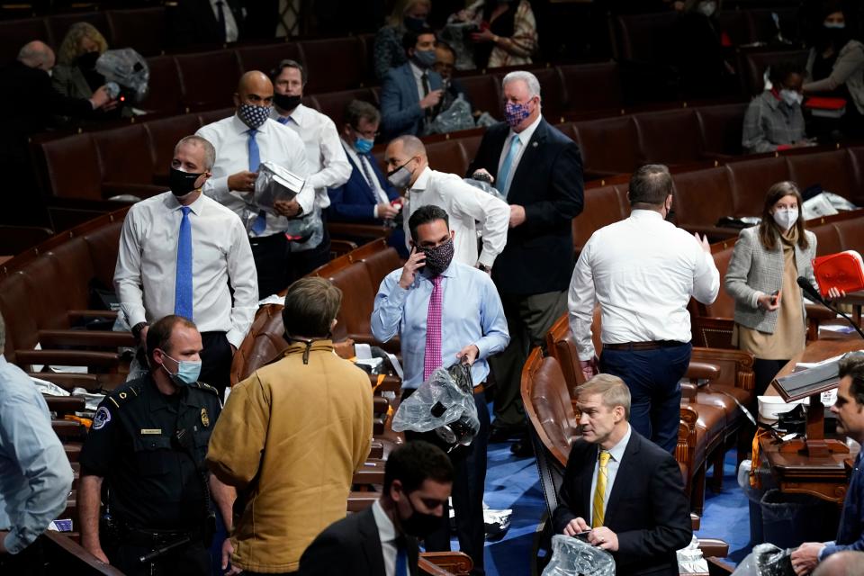 Lawmakers put on masks on the floor of the House of Representatives as a mob enters the U.S. Capitol on Jan 6.