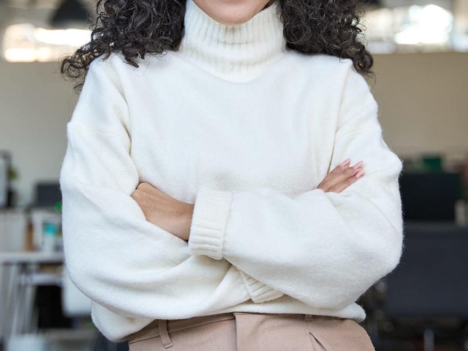 woman wearing a cream sweater and brown trousers in an office