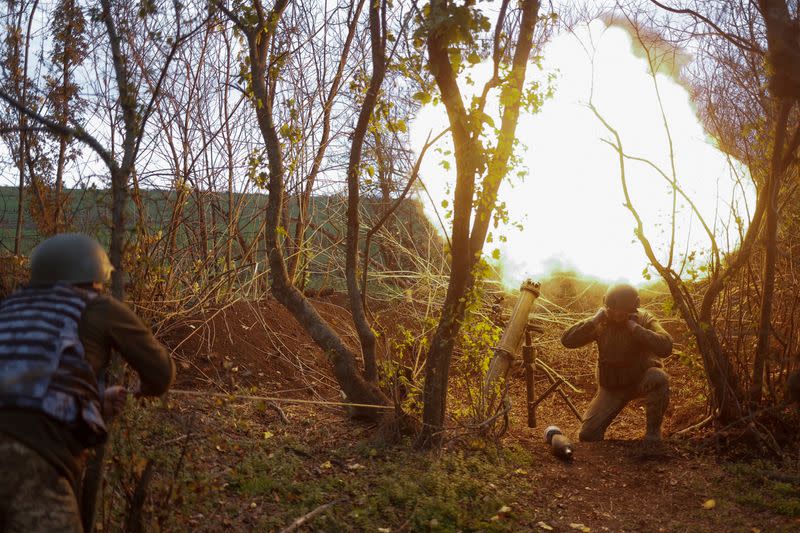 Ukrainian servicemen fire with a mortar toward Russian positions in a frontline in Mykolaiv region