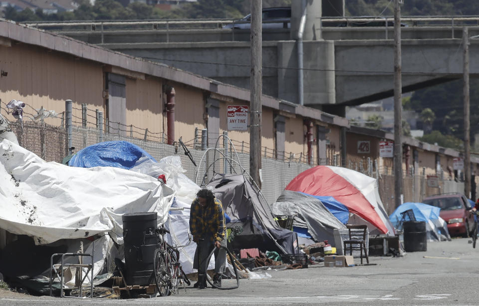 A man holding a bicycle tire outside of a tent along a street in San Francisco on&nbsp;June 27, 2019. (Photo: ASSOCIATED PRESS)