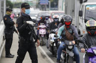 Police operate a checkpoint Tuesday, Aug. 4, 2020, outside Manila, Philippines, as the capital is placed on another lockdown in the hopes of controlling the surge of coronavirus cases. Commuter trains, buses and other public vehicles stayed off the main roads of the Philippine capital Tuesday and police were again staffing checkpoints to restrict public travel. (AP Photo/Aaron Favila)