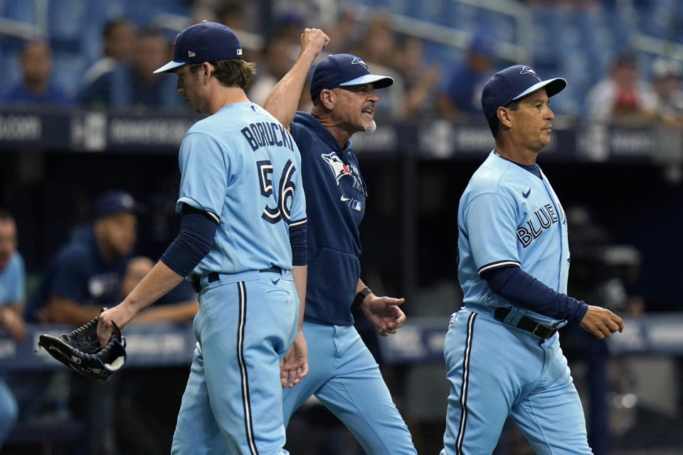 Toronto Blue Jays manager Charlie Montoyo, right, and pitching coach Pete Walker, center, run onto the field after starting pitcher Ryan Borucki, left, was ejected after hitting Tampa Bay Rays' Kevin Kiermaier with a pitch during the eighth inning of a baseball game Wednesday, Sept. 22, 2021, in St. Petersburg, Fla. (AP Photo/Chris O'Meara)