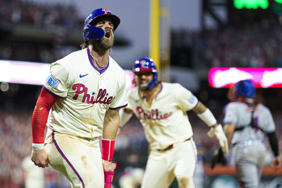 Philadelphia Phillies' Bryce Harper, left, and Nick Castellanos celebrate after scoringon a two-run triple hit by Bryson Stott during the eighth inning of Game 2 of a baseball NL Division Series against the New York Mets, Sunday, Oct. 6, 2024, in Philadelphia. (AP Photo/Matt Slocum)