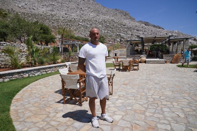 Agia Marina bar manager Ilias Tsavaris, 38, speaks to the media on Symi with a rocky hill behind him