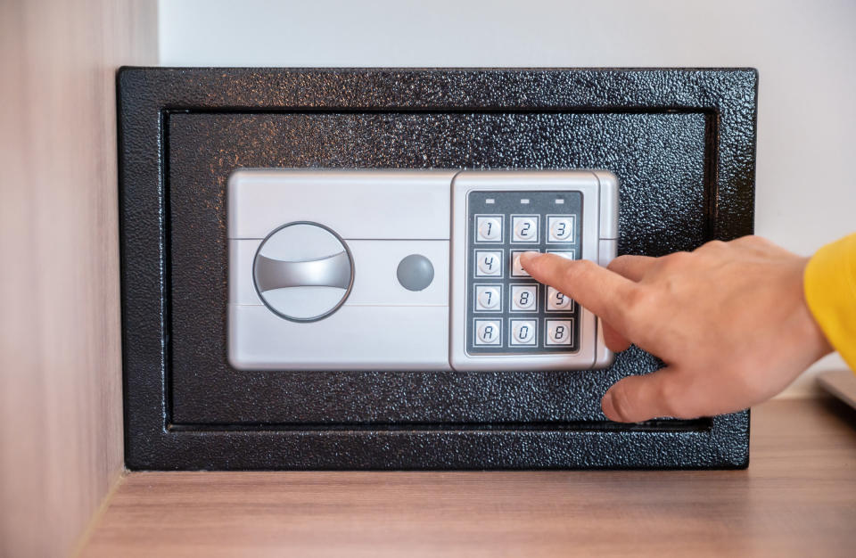 A hand entering a code into a hotel safe.