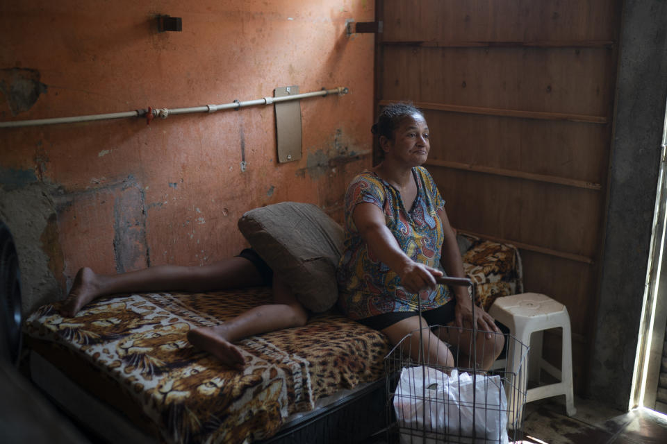 Sandra Brito, 55, sits on her bed after carrying a grocery caddy filled with food donated by the Rio de Paz NGO amid the COVID-19 pandemic in the Mandela slum, in Rio de Janeiro, Brazil, Saturday, March 27, 2021. (AP Photo/Felipe Dana)