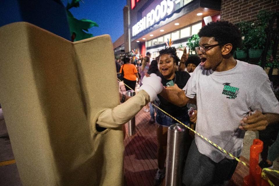 Devin Vato, left, shakes hands with an HEB mascot during the grand opening of HEB on Wednesday, June 26 in Mansfield. Cato waited in line since 6pm on Monday and is his first time at HEB.