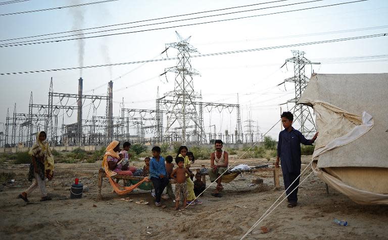 A displaced family sits by its tent in front of DPS thermal power station in Muzaffargah, Punjab province, Pakistan, on September 5, 2010 following floods across the region