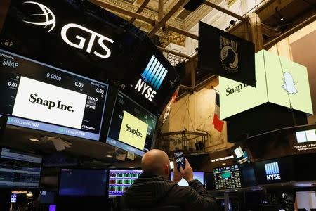 A man photographs Snap Inc. logos on the floor of the New York Stock Exchange (NYSE) on the eve of the company's IPO in New York, U.S., March 1, 2017. REUTERS/Brendan McDermid