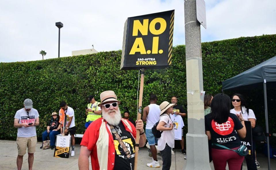 Una persona con un cartel en contra de la IA durante la huelga de guionistas