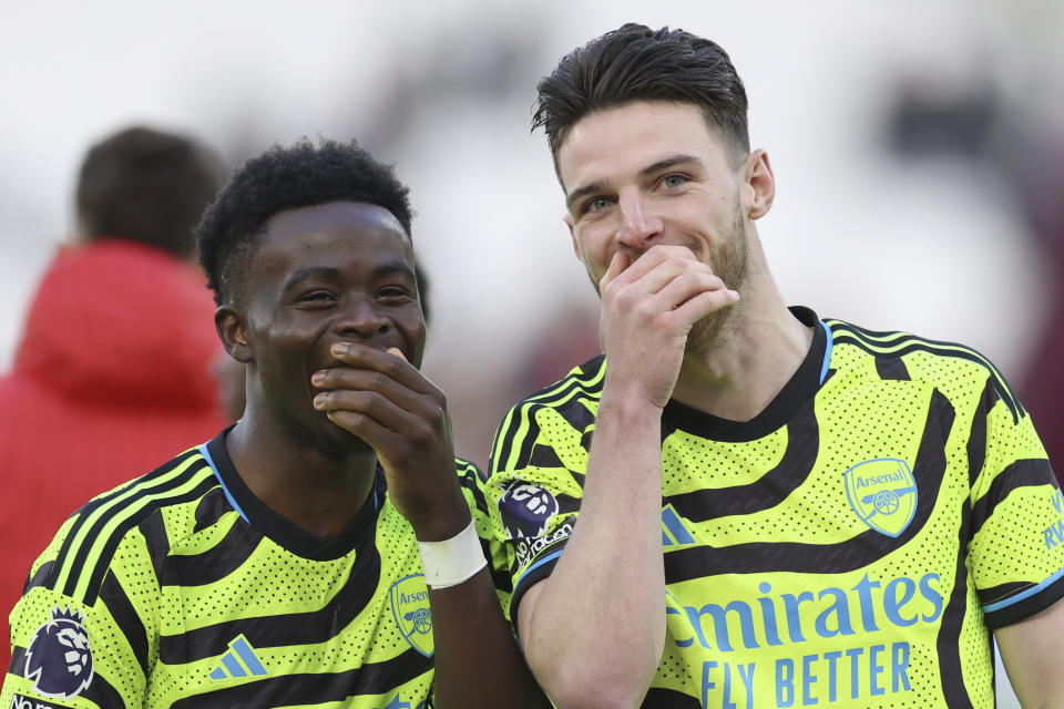 Arsenal's Declan Rice, right smiles as he talks to teammate Arsenal's Bukayo Saka after the end of the English Premier League soccer match between West Ham United and Arsenal at the London Stadium in London, Sunday, Feb. 11, 2024. Arsenal won the game 6-0, Rice scored a goal and had two assists against his former club.(AP Photo/Ian Walton)