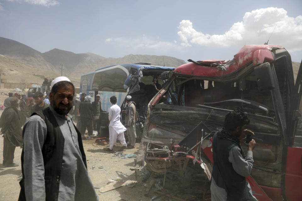 Afghan men stand near damaged buses after a deadly accident on the Kabul-Kandahar highway, on the outskirts of Kabul, Afghanistan, Tuesday, April 27, 2021. Two buses crashed head-on killing several people and injuring more than 70, an Afghan official said Tuesday. (AP Photo/Rahmat Gul)