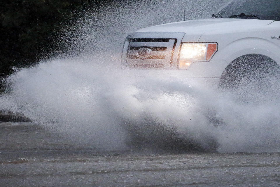 A vehicle travels along a flooded road as severe weather produces torrential rainfall, Tuesday, May 4, 2021 in Vestavia, Ala. (AP Photo/Butch Dill)