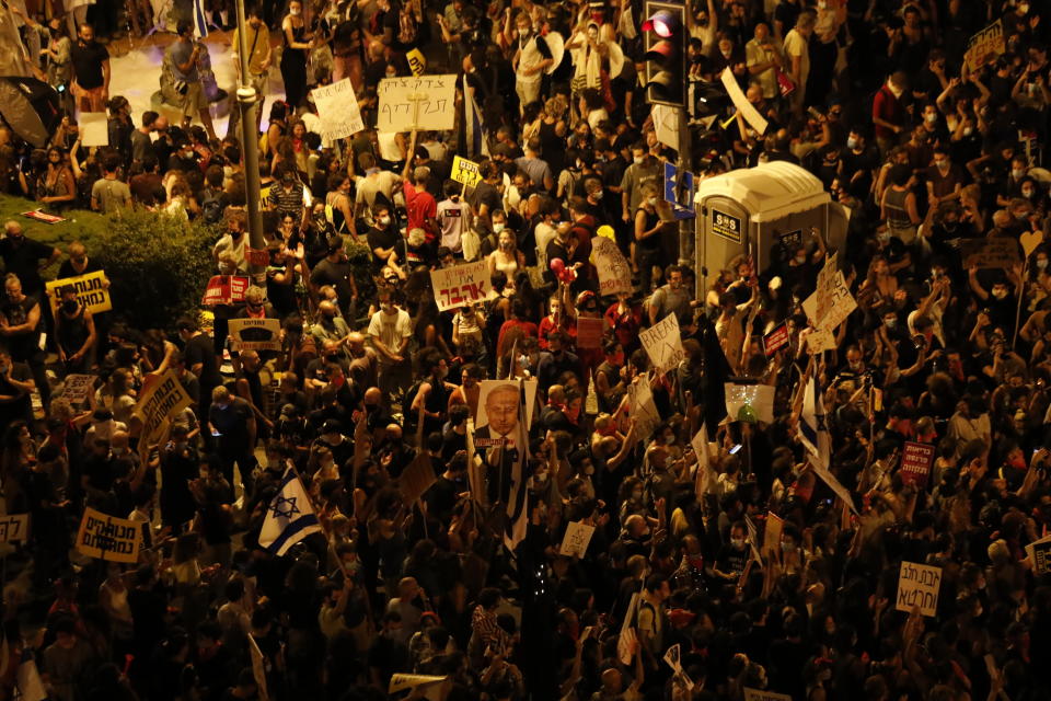 Thousands of demonstrators chant slogans and hold signs during a protest against Israel's Prime Minister Benjamin Netanyahu outside his residence in Jerusalem, Saturday, July 25, 2020. Protesters demanded that the embattled leader resign as he faces a trial on corruption charges and grapples with a deepening coronavirus crisis. (AP Photo/Ariel Schalit)