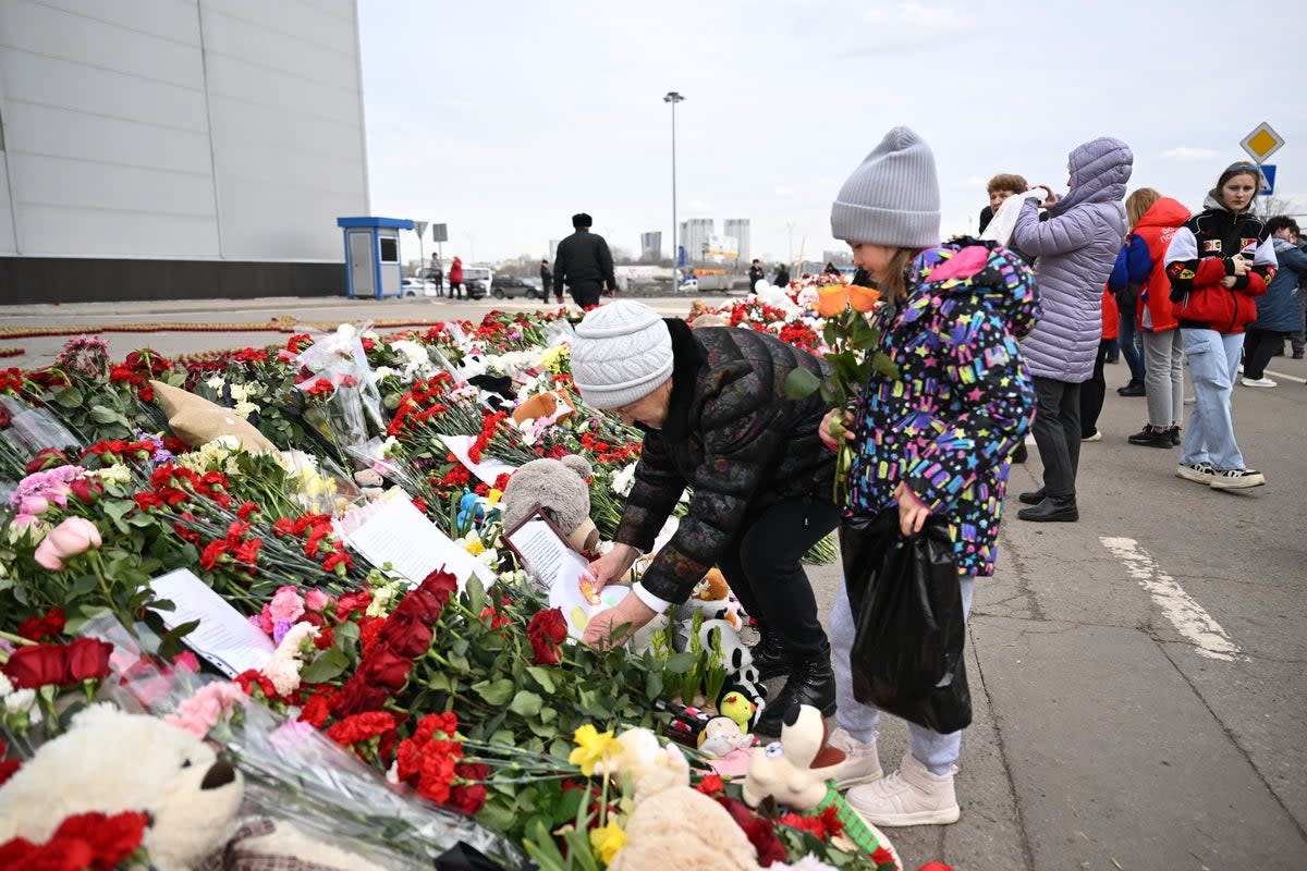 A woman places a drawing at a makeshift memorial in front of the burnt-out Crocus City Hall concert venue in Krasnogorsk, outside Moscow (AFP via Getty Images)