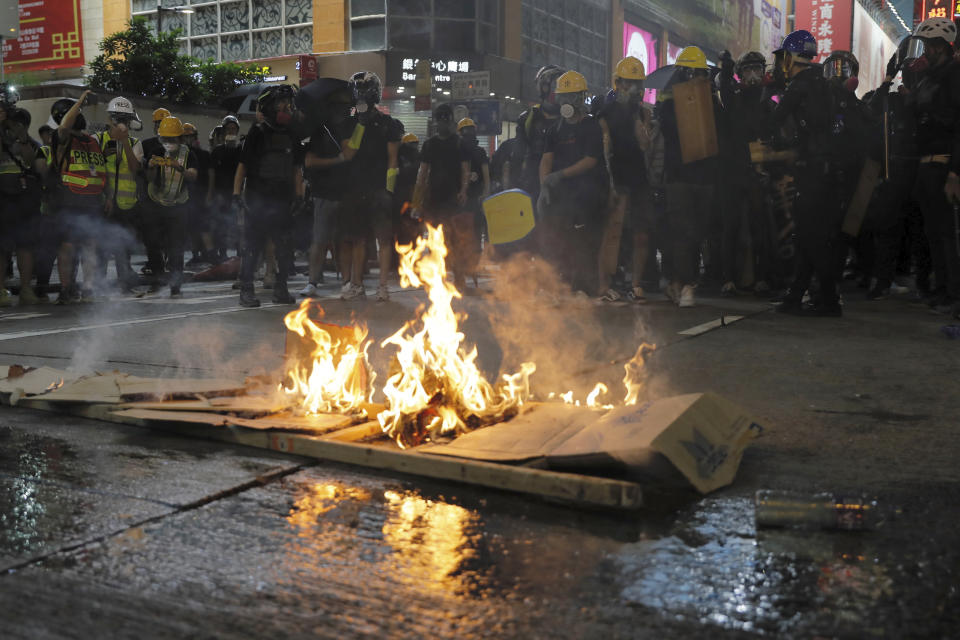 Protesters burn cardboard to form a barrier as they confront with police in Hong Kong on Saturday, Aug. 3, 2019. Hong Kong protesters removed a Chinese national flag from its pole and flung it into the city's iconic Victoria Harbour on Saturday, and police later fired tear gas at demonstrators after some of them vandalized a police station. (AP Photo/Kin Cheung)