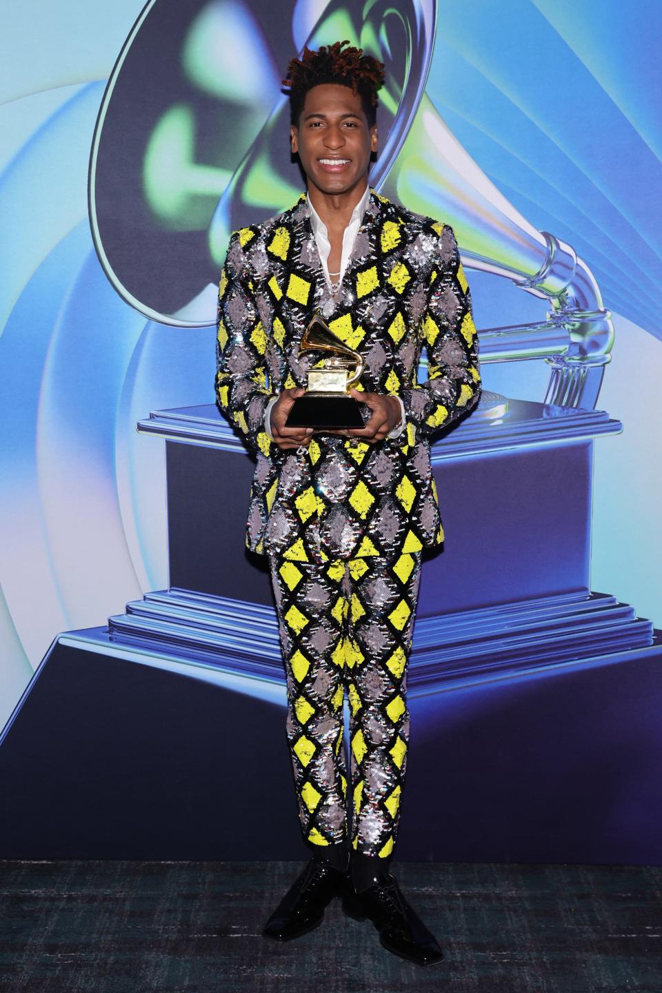 Jon in a yellow and shiny silver diamond print blazer and pants.