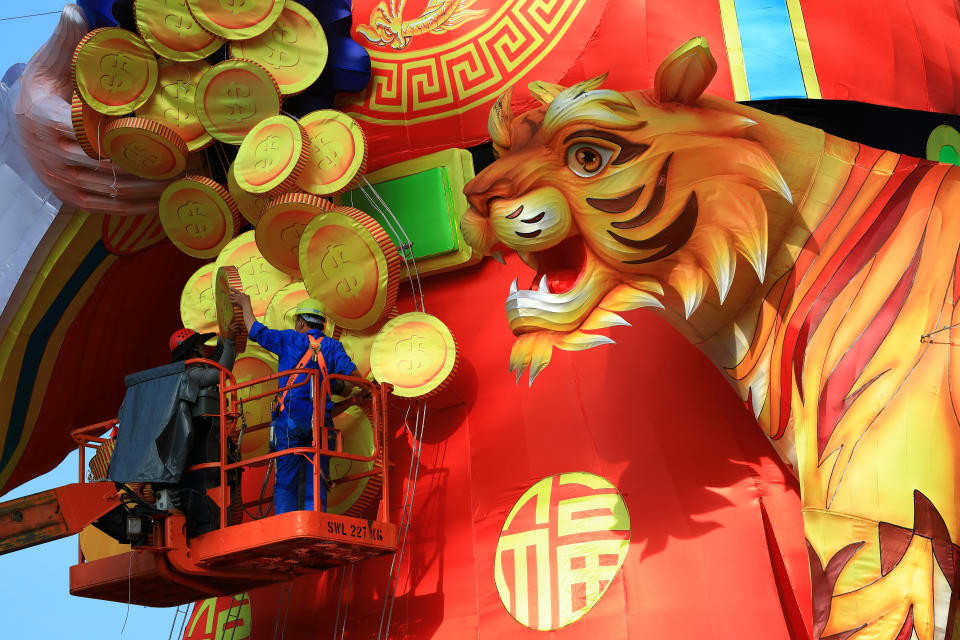 Workers put up decorative gold coins on a giant lantern display featuring the God of Fortune next to a tiger as Singapore prepares to usher in the Year of the Tiger amid the rise in the Omicron variant cases during the COVID-19 pandemic at the Supertree Grove, Gardens by the Bay on January 16, 2022 in Singapore. On February 1, people around the world will welcome the Year of the Tiger, one of the most anticipated holidays on the Chinese calendar. Also known as the Spring festival or the Lunar New Year, the celebrations last for about 15 days. 
 (Photo by Suhaimi Abdullah/NurPhoto via Getty Images)