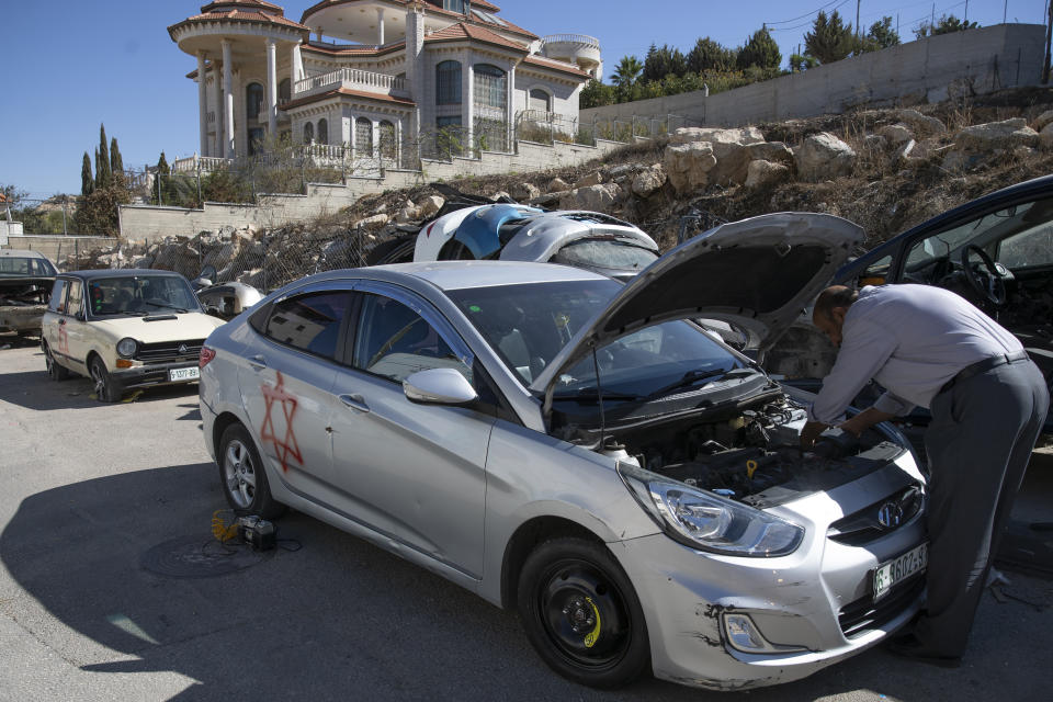 A Palestinian man works on his vandalized vehicle painted with the Star of David after suspected Israeli settlers vandalized residents properties overnight in the West Bank city of Ramallah, Tuesday, Nov. 9, 2021. It was the latest in a series of so-called “price tag” attacks, in which hard-line Israeli nationalists attack Palestinians and vandalize their property in response to Palestinian militant attacks or perceived efforts by Israeli authorities to limit settlement activity. (AP Photo/Nasser Nasser)