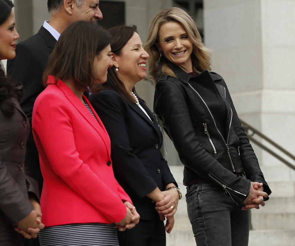 FILE -- In this April 1, 2019 file photo California First Partner Jennifer Siebel Newsom, the wife of Gov. Gavin Newsom, right, talks with Lt. Gov. Eleni Kounalakis, center, for a news conference to announce the #EqualPayCA campaign, in Sacramento, Calif. Siebel Newsom has shunned the traditional title of "first lady" and is focusing on women's issues including equal pay and expanding family leave. (AP Photo/Rich Pedroncelli, File)